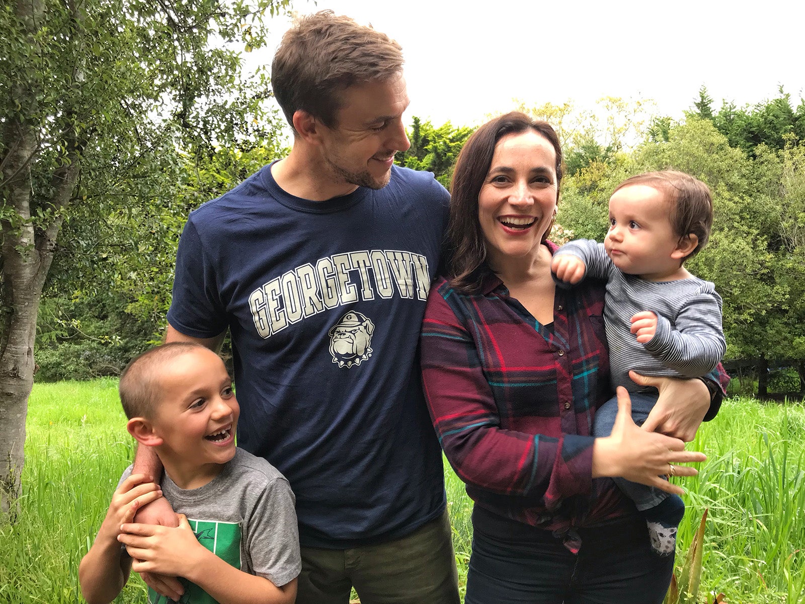 Mark and Giulia smile in April 2019 while holding their two children Jonas and Cosimo in a wooded clearing during a family outing to a favorite spot in California called Point Reyes.