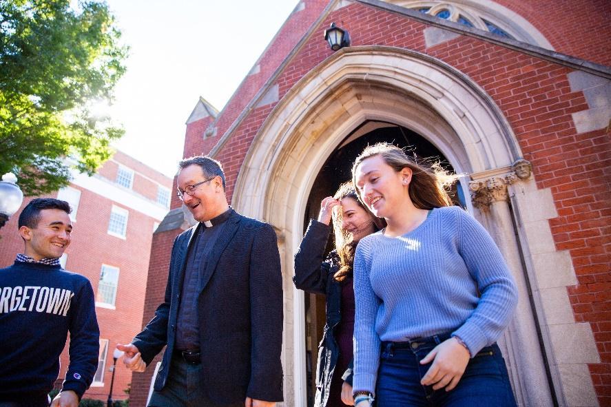 Rev. Bosco walking and talking with students on campus.